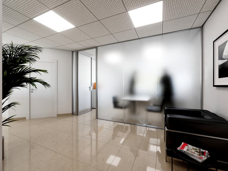 The image shows a modern office space with a tiled floor, white walls, and a suspended ceiling with recessed lighting. There is a potted plant in the corner, and a black office chair in the foreground. The room appears to be well-lit and has a clean, prof