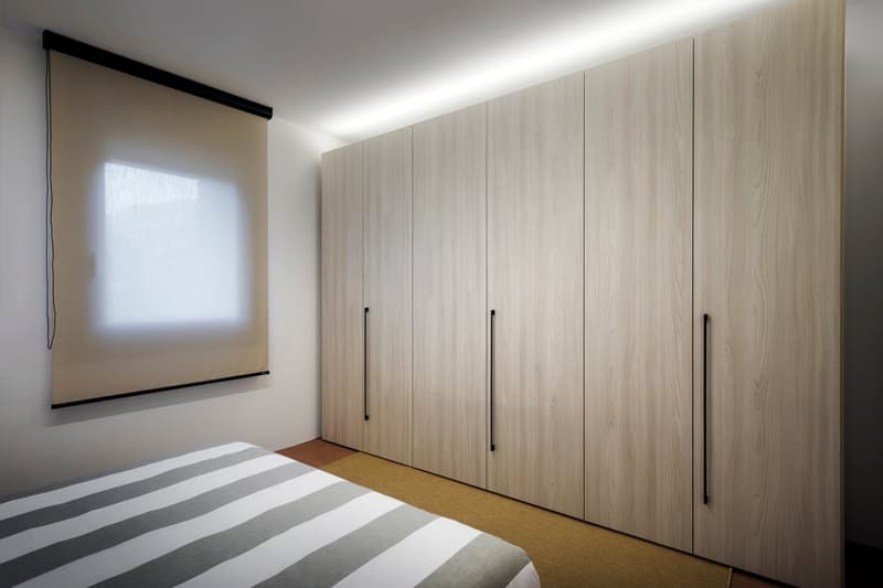 Spacious bedroom with large built-in wardrobe along one wall, hardwood-style flooring, and a projector screen mounted on the wall.