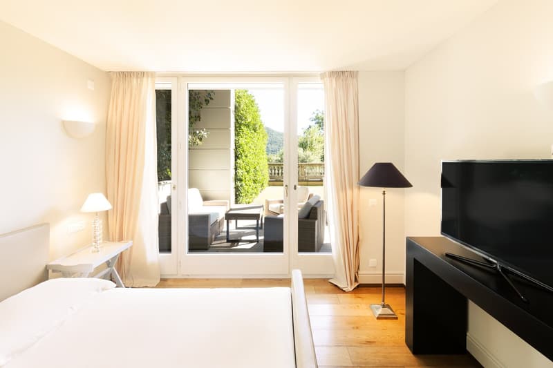 white walls, white bed, white nightstand, sliding doors to balcony, outdoor furniture, flatscreen TV