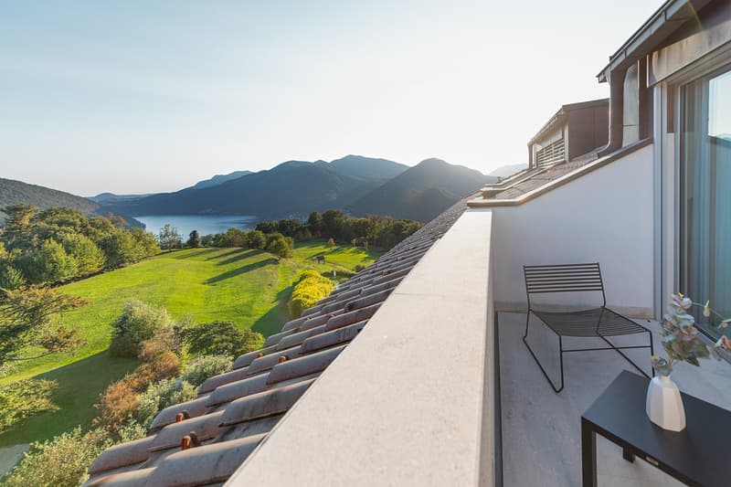 Balcony with a beautiful view of the mountains and the lake, a table, and a vase
