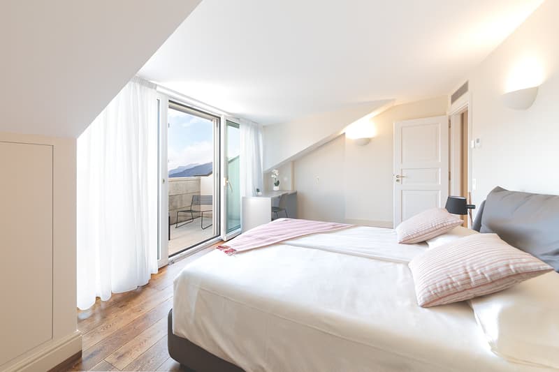 large bed, wooden floor, sliding glass door to balcony, daylight, minimalist decor, clean and bright