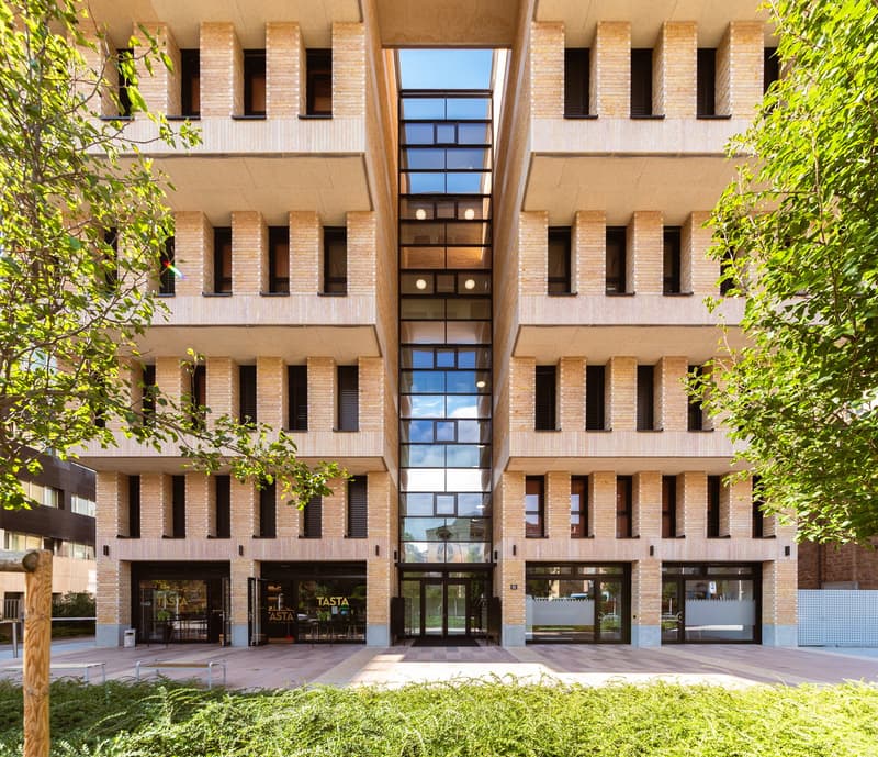 Multi-story apartment building, brick walls, large windows, central courtyard