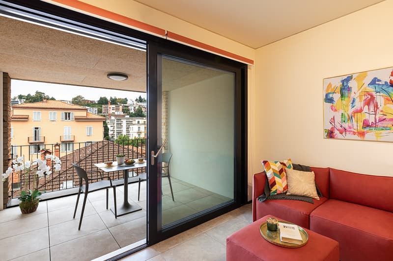 Balcony with a table, couch, pillows, book on a coffee table