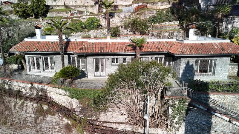 two-story house, stone exterior, red roof, three chimneys, three windows on each floor, balconies on each side, stone walls