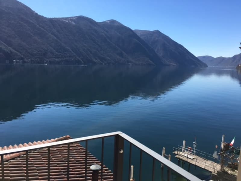 Balcony with metal railing overlooking a lake with mountains in the background