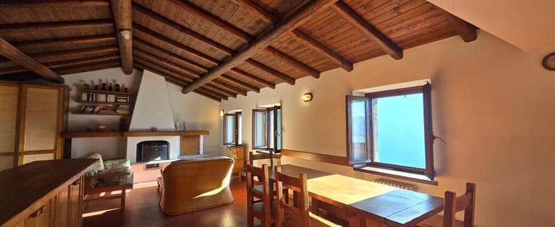 exposed wooden beams, wooden dining table, wooden cabinet, fireplace, radiator, chair, couch, lamp