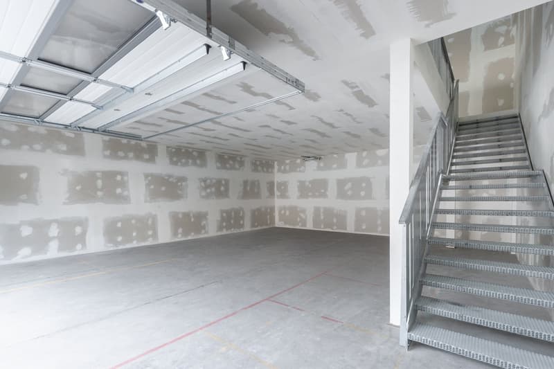 Empty garage with unfinished walls, metal stairs, and a metal handrail.
