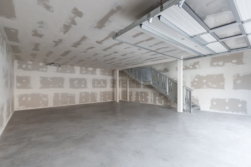Empty room, concrete floor, unfinished walls, metal staircase, metal garage door