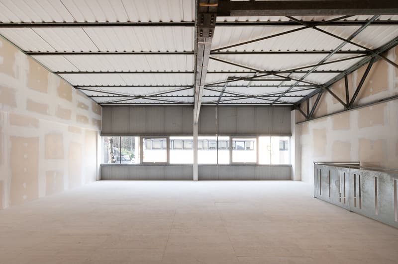 Empty room with white walls, metal ceiling, large windows, tiled floor, metal railings