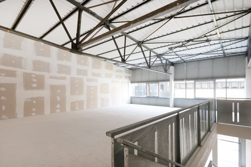 Industrial building, unfinished interior, metal beams, white walls, tiled floor, staircase, windows