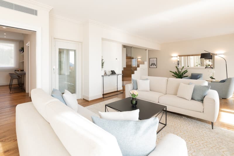 modern living room with white couches, black coffee table, wooden floor, white walls, mirror, plants, lamps