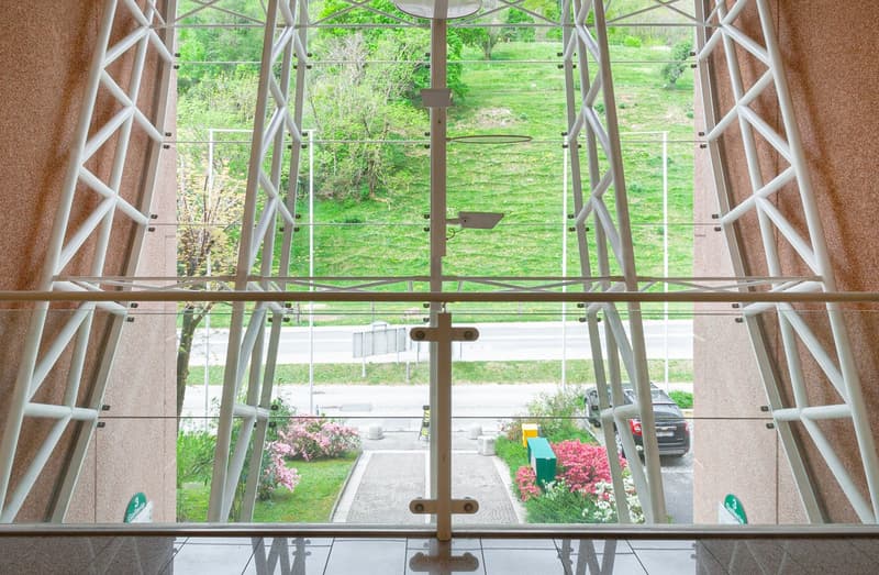 modern building with glass walls, metal frame, view of a green field and road
