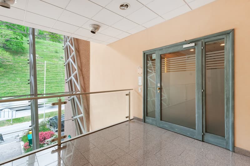 Balcony with glass railing, tiled floor, double glass doors, surveillance camera, outdoor view