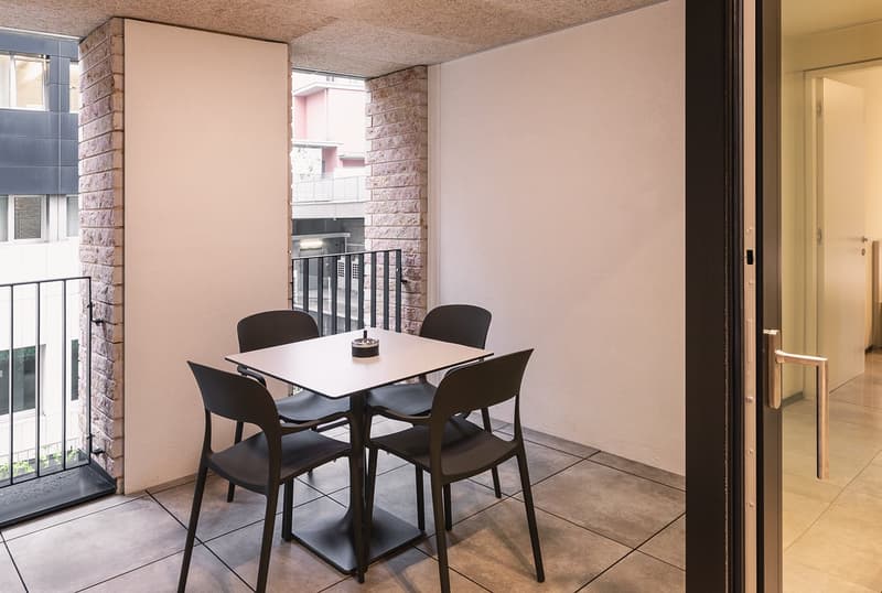 Balcony with table and chairs, brick wall, tiled floor, glass door
