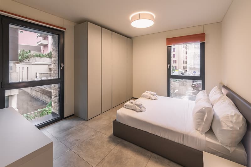 bedroom with bed, wardrobe, windows, tiled floor, ceiling lamp