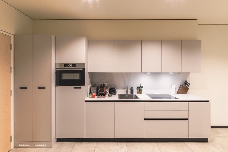 modern kitchen with white cabinets, black countertops, built-in oven, sink, and dishwasher