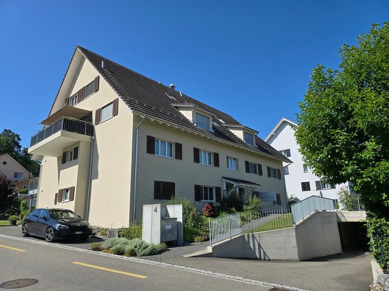 Three-story beige house, black roof, white windows, garage entrance, balcony