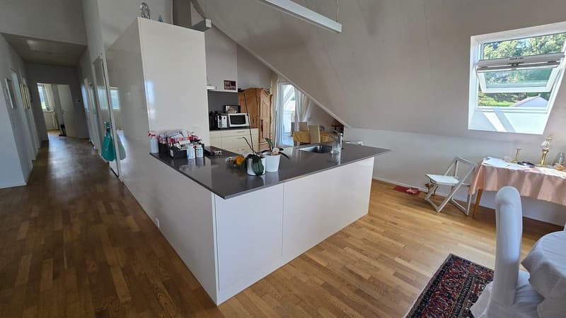 kitchen with island, wooden floor, white walls, large window, wooden cabinet, microwave, sink, countertop, dining table, chairs, rug