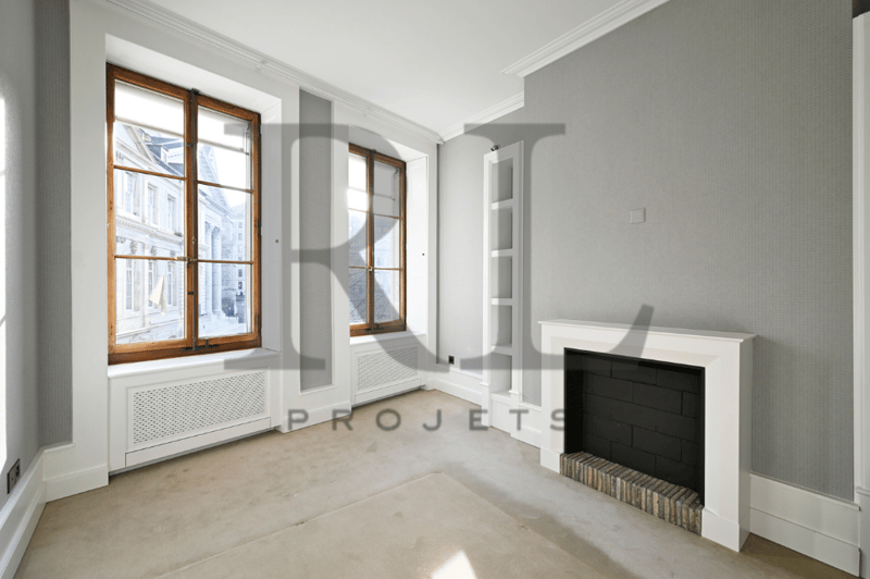Spacious living room with large windows, hardwood floors, and a fireplace