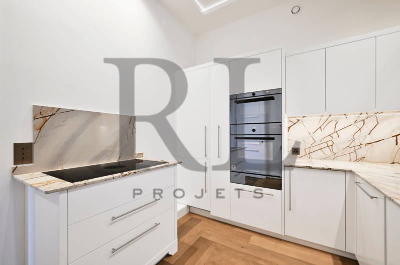 Modern kitchen with white cabinets, marble countertops, built-in oven and dishwasher, hardwood flooring