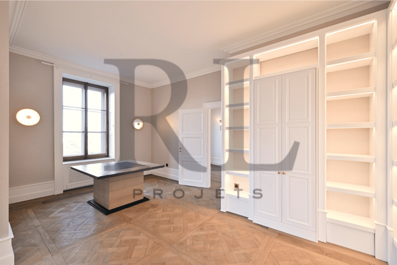 Spacious living room with hardwood parquet flooring, white built-in cabinets and shelves, large window, and a fireplace