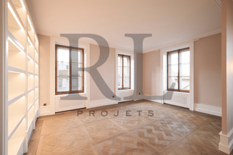 Spacious room with large windows, hardwood flooring in a herringbone pattern, and white walls. The room appears to be a living or dining area.