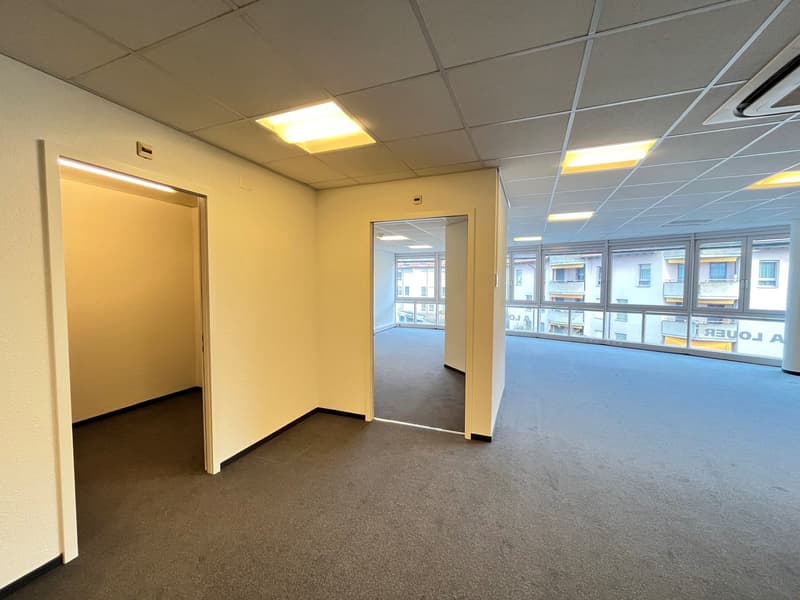 Empty room with windows, two doors, gray carpet, and white walls