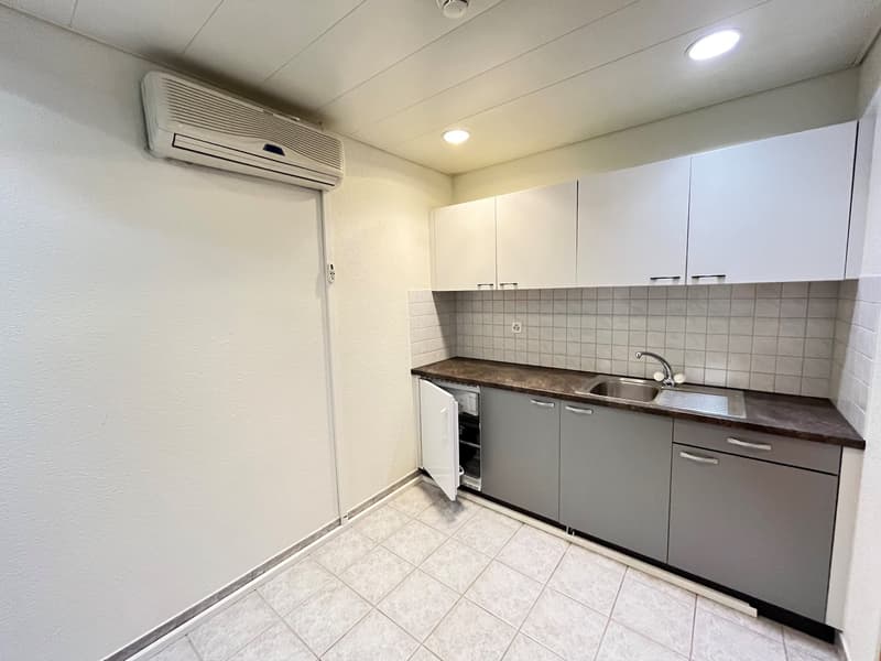 White kitchen with tile floor, stainless steel sink, grey cabinets, air conditioner, open refrigerator