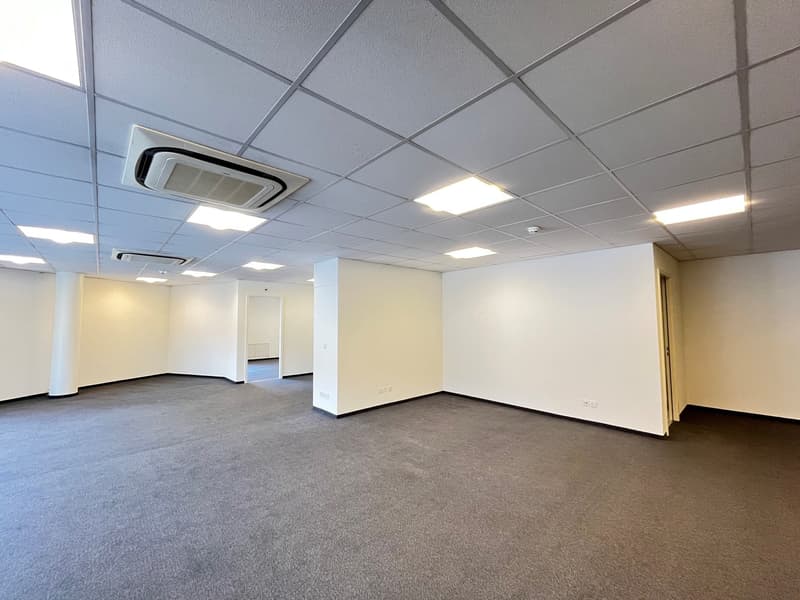 Empty room with ceiling air conditioning, white walls and carpeted floor