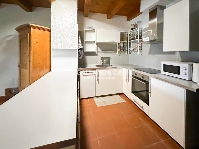 modern kitchen with white cabinets, wooden floors, gas stove, and white oven, small sink with faucet, white microwave, and a wooden cupboard