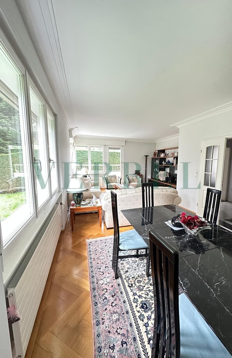 / a living room and dining room with large windows and a table and chairs in the center of the room