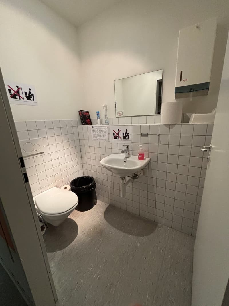 a small bathroom with a toilet, sink, and mirror