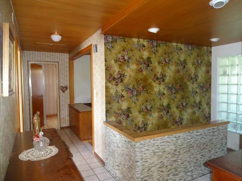Wooden ceiling, hallway, white tiles, floral wallpaper, desk with decorative items, statue, open door