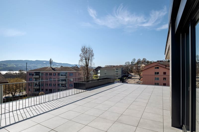 Rooftop terrace with tiled floor, metal railings, and a view of the city and mountains
