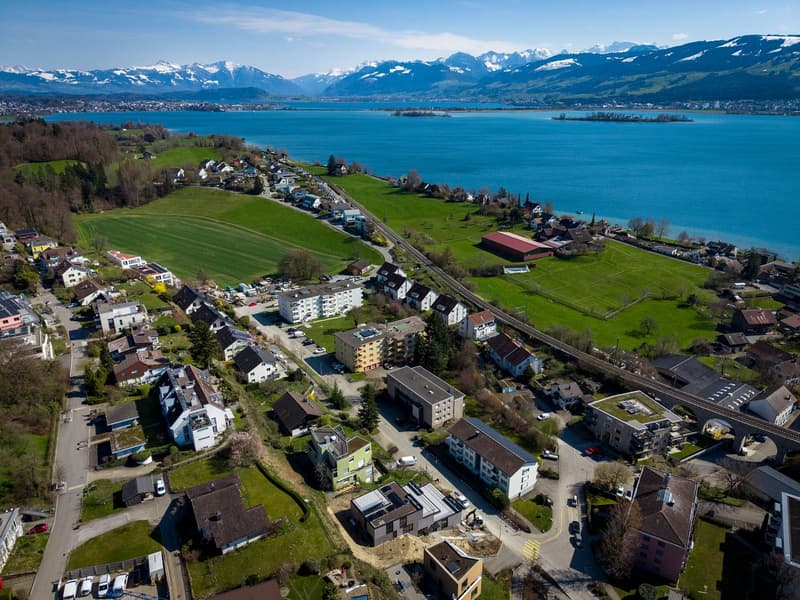 Aerial view of a town with houses, a lake, and mountains in the background