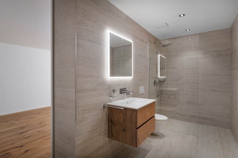 modern bathroom with wooden floor, white sink, wooden cabinet, glass shower, mirror, toilet