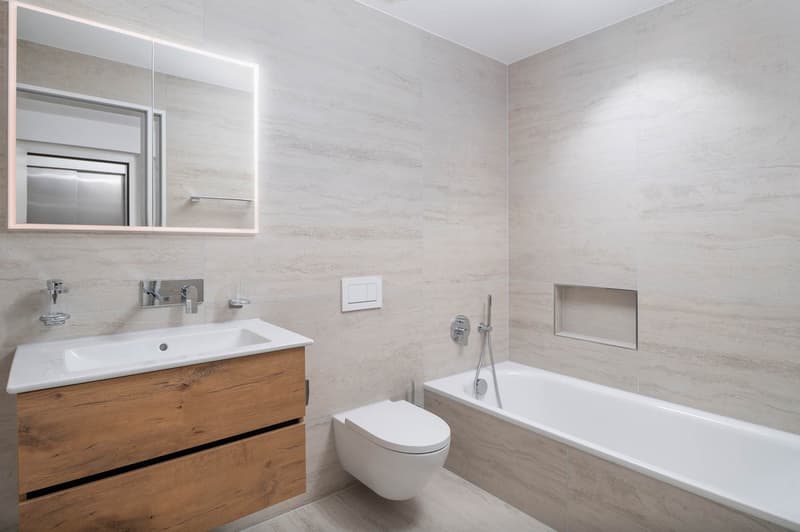 modern bathroom with white tiles, wooden cabinet, white sink, white toilet, bathtub, mirror