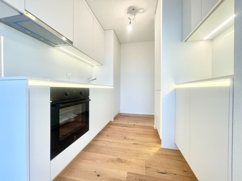 modern kitchen with white cabinets, wooden floor, black oven, sink with faucet, white walls