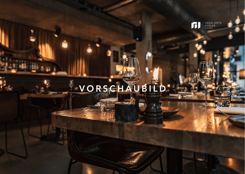 A restaurant with wooden tables and chairs, wine glasses, plates, and a candle on the table.
