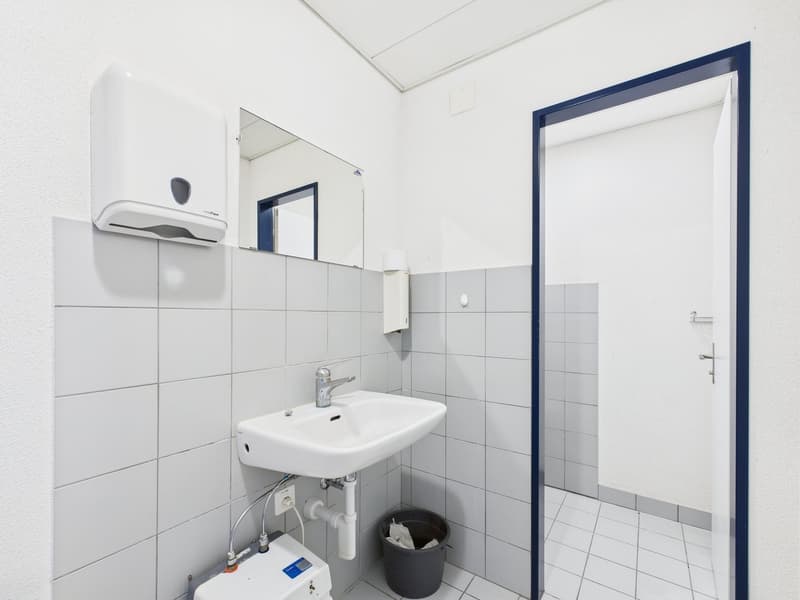 tiled floor, white sink, mirror, paper towel dispenser, power outlet, trash can, soap dispenser