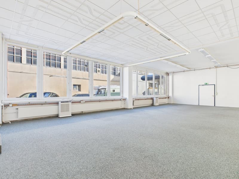 Empty room with gray carpeted floor, large windows with white frames, and white walls