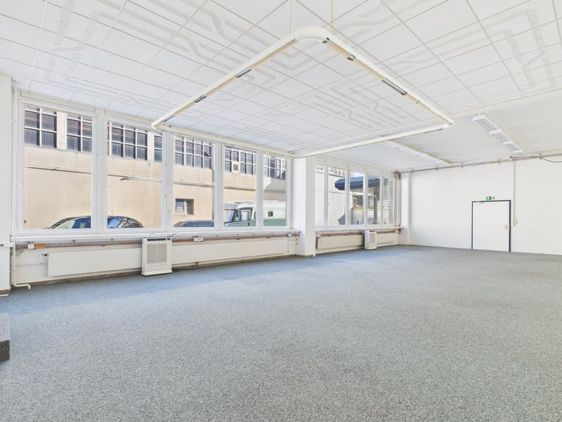 open room with large windows, high ceiling, gray flooring, two air conditioners, white doors