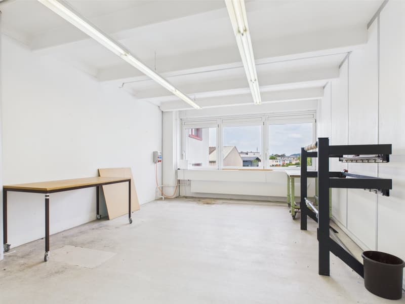 Empty room with white walls, wheels table, industrial lighting, window with view