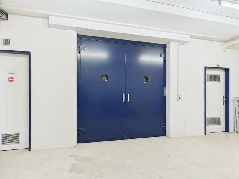 Empty room with large blue doors, and white walls, air ventilation on walls