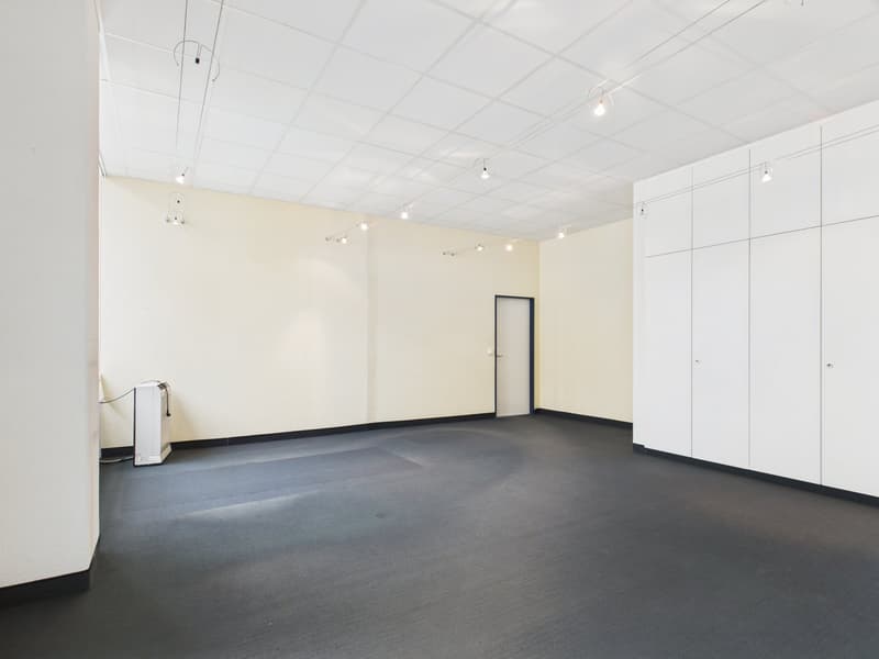 empty room with white walls, grey floor, door, white cabinets