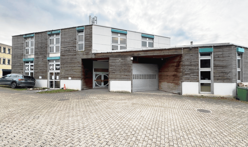 Wooden exterior, 2 floors, large garage, multiple windows, grey car parked