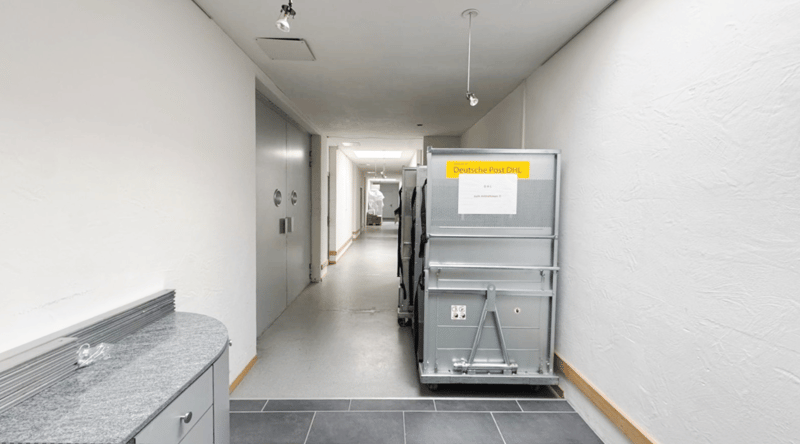 a clean, empty corridor with grey tile flooring, grey cabinets and storage units