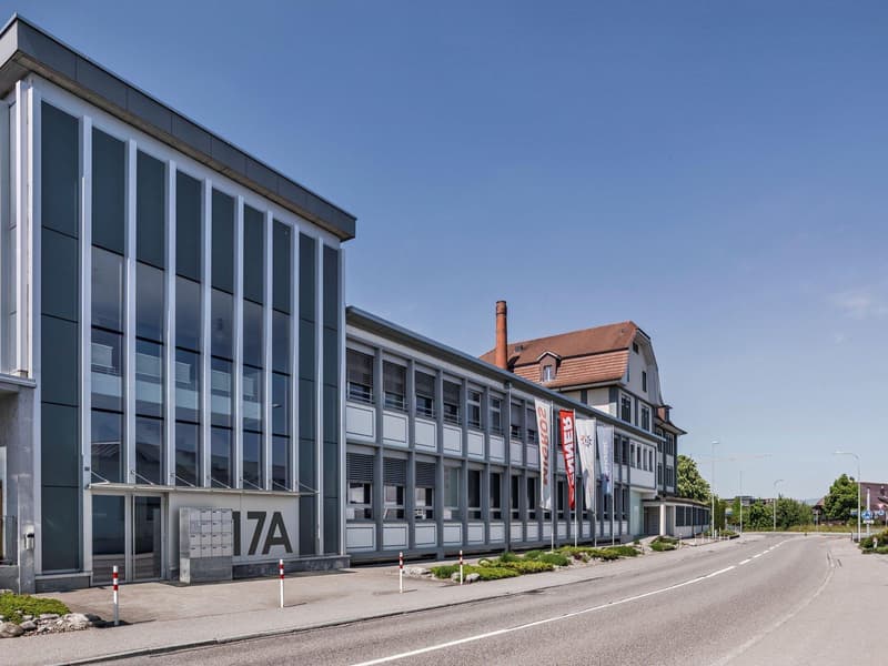 Modern office building with glass walls, multiple floors, and several banners along the wall.