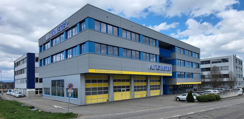 modern office building, steel blue and white exterior, yellow garage doors, multiple windows, parking lot, surrounding cars