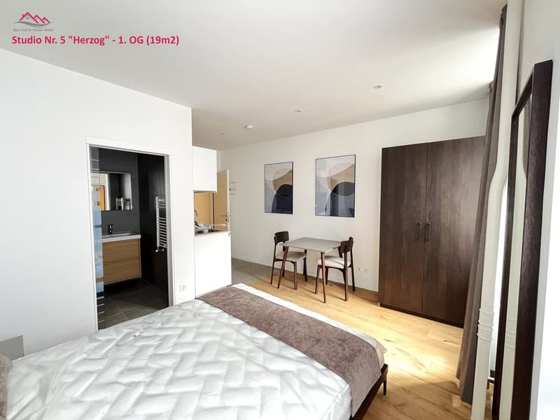 modern studio with double bed, table, chairs, sink, wooden floor, wardrobe